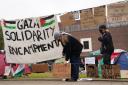 A student adjusts a sign at an encampment on the grounds of Newcastle University, protesting against the war in Gaza (Owen Humphreys/PA)